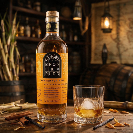 Schwarzbach Spirits Berry Bros. & Rudd Guatemala Rum Flasche neben einem Glas mit Eis auf einem rustikalen Holztisch