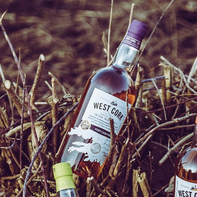 Schwarzbach Spirits West Cork Port Cask Finish Irish Single Malt whiskey bottle resting in rustic dry branches