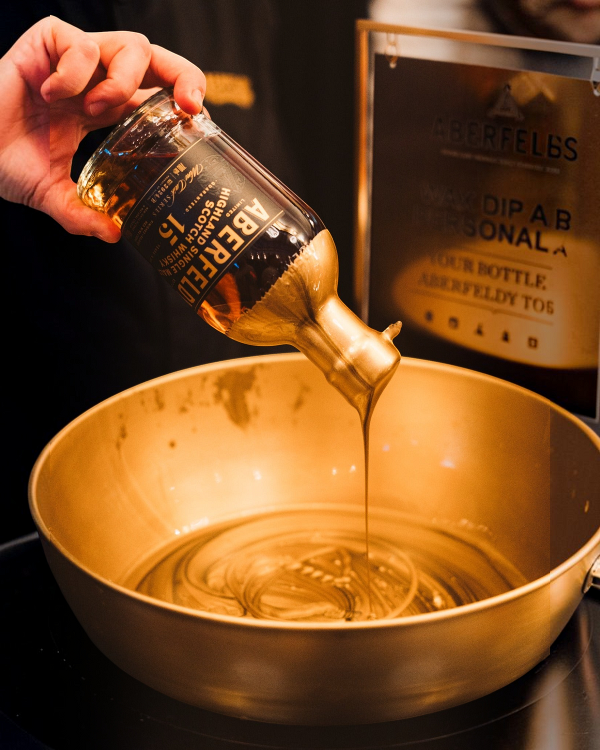 Schwarzbach Spirits Aberfeldy Whiskyflasche wird von Hand in flüssiges goldenes Wachs getaucht zur Personalisierung