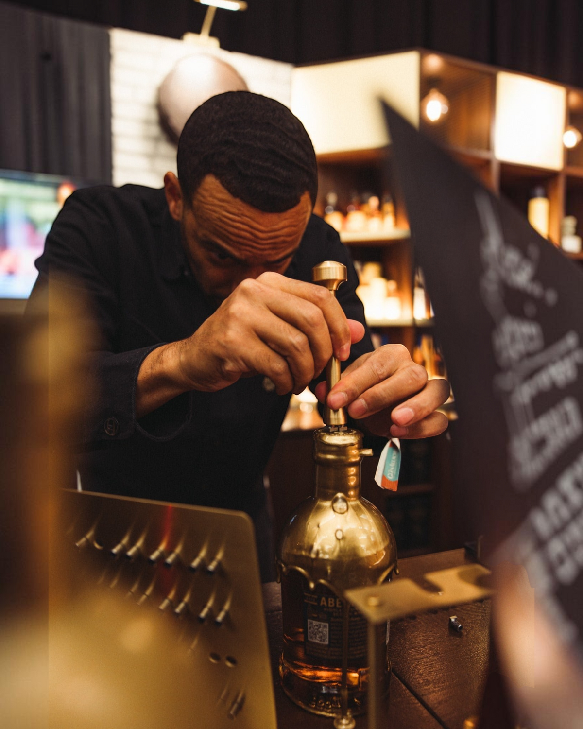 Schwarzbach Spirits Mitarbeiter beim manuellen Wachsversiegeln einer Aberfeldy Whiskyflasche mit goldenem Wachs