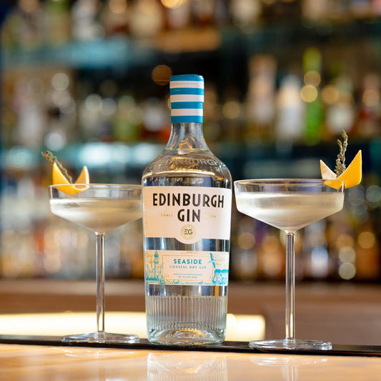 Schwarzbach Spirits Edinburgh Gin Seaside Coastal Dry Gin bottle with two cocktails garnished with orange peel and herbs.
