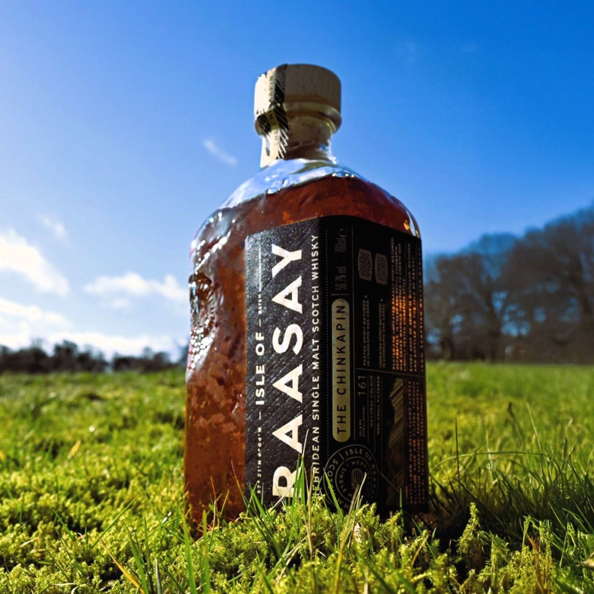 Schwarzbach Spirits bottle of Isle of Raasay The Chinkapin Single Malt Scotch Whisky standing in a grassy field.