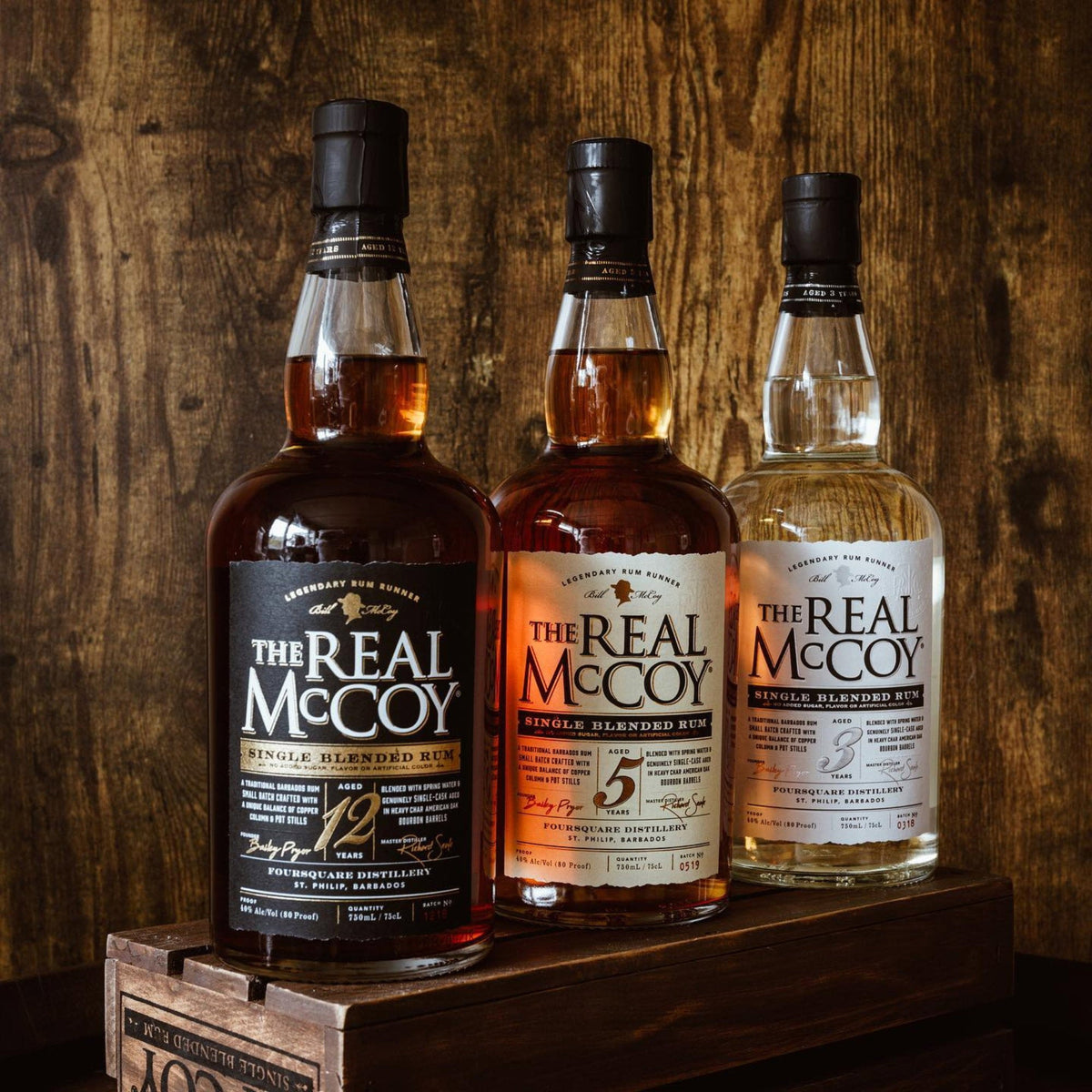 Schwarzbach Spirits The Real McCoy Rum Flaschen mit 3, 5 und 12 Jahren Reifung vor einer rustikalen Holzoberfläche.