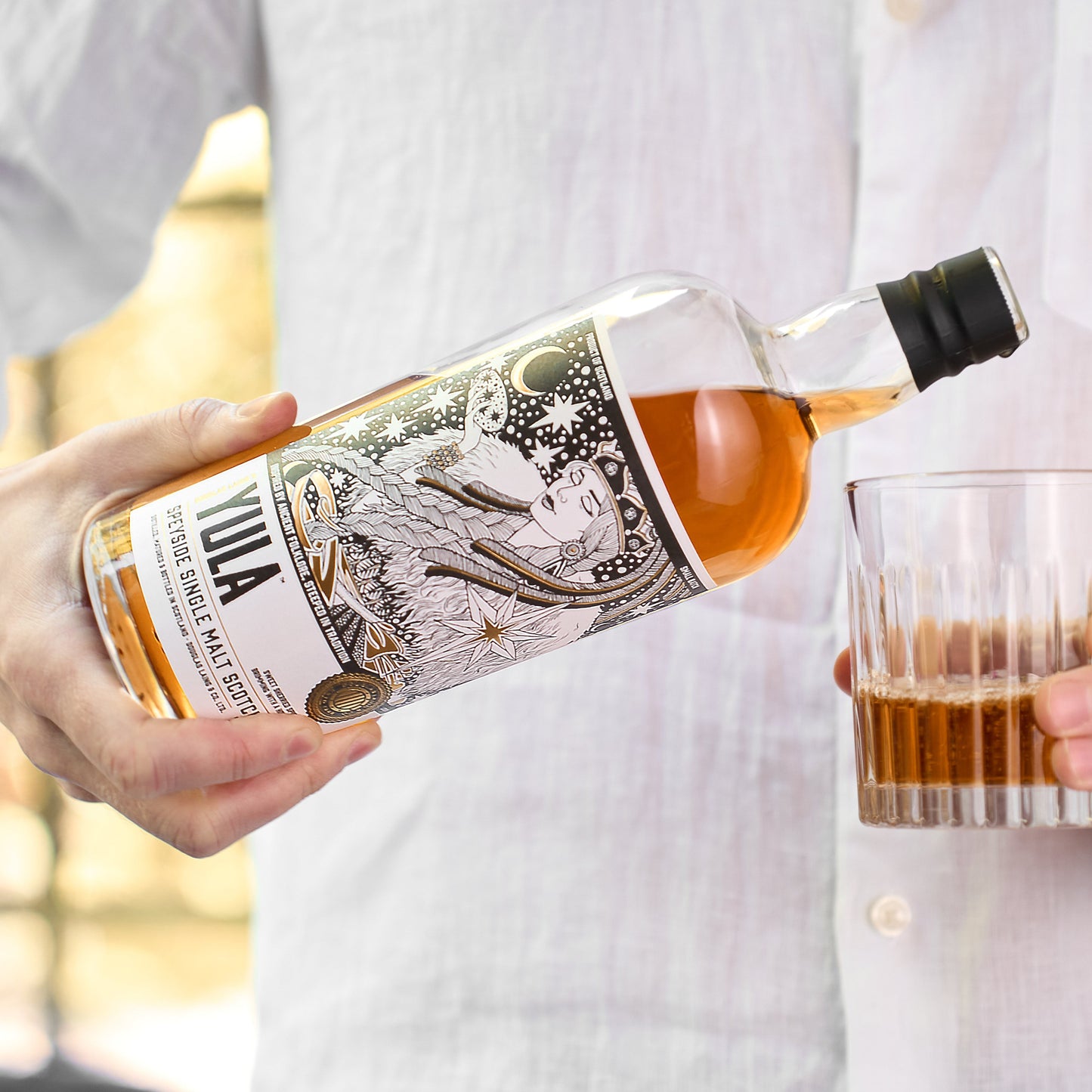 Schwarzbach Spirits YULA Speyside Single Malt Scotch Whisky wird in ein Glas eingeschenkt, mit kunstvollem Etikett.